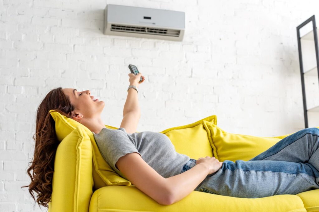 woman feeling hot on sofa turning up ac